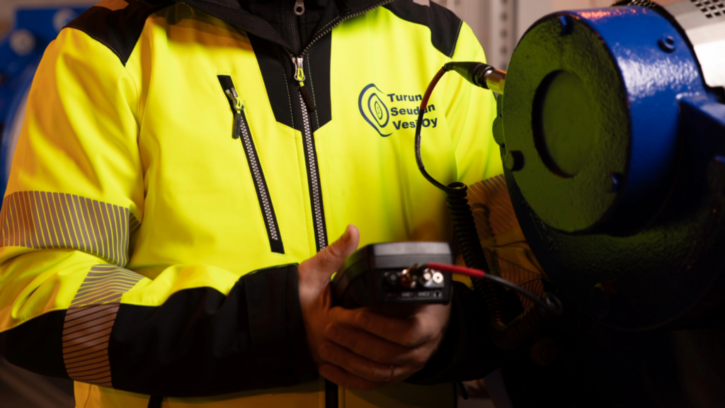 Ihminen työtakissa pitää laitetta käsissään