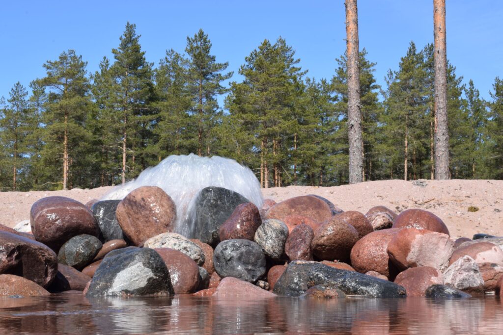Vettä valuu kivien väliin. Taustalla metsää